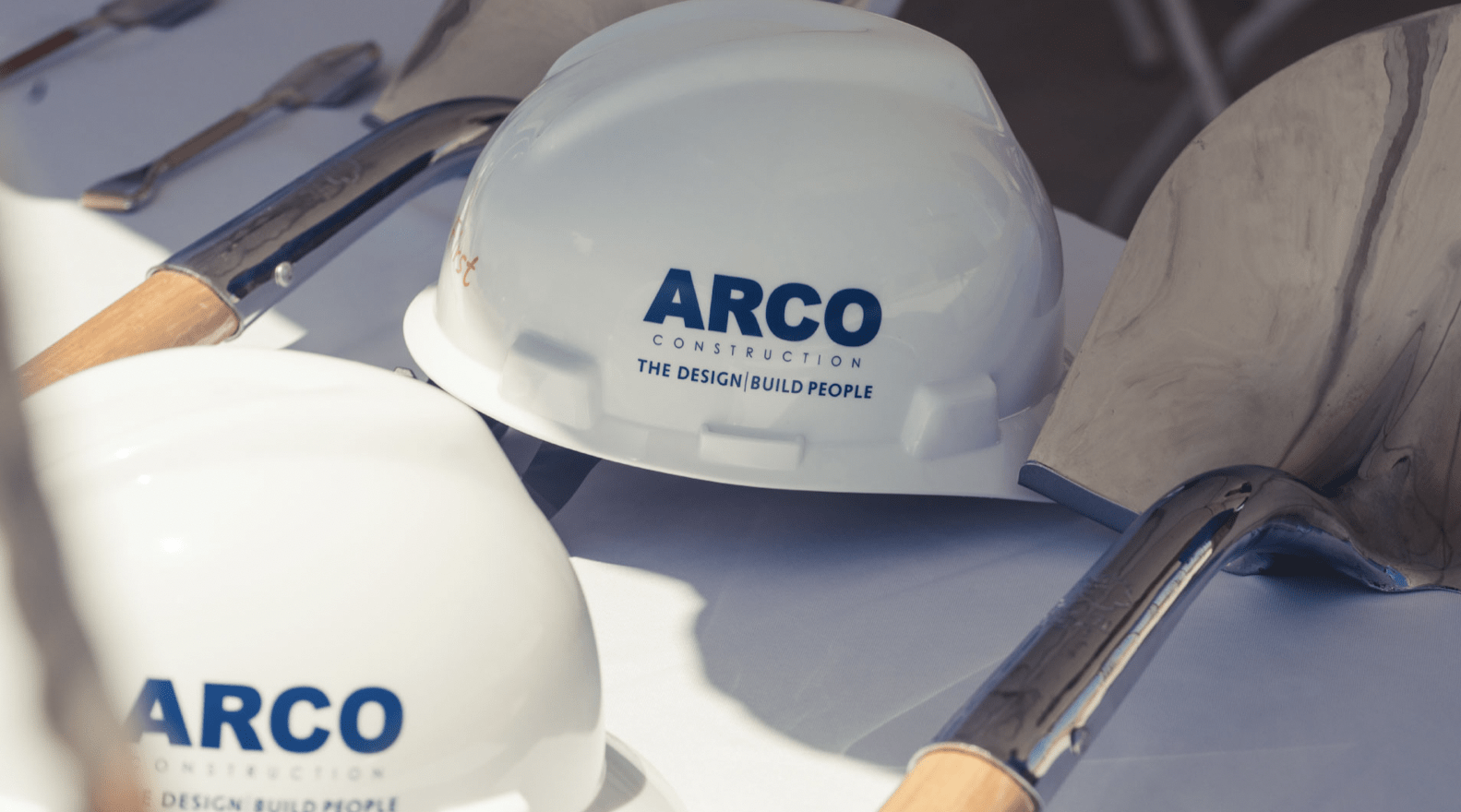 ARCO Construction hard hats and shovels on display at a construction event.